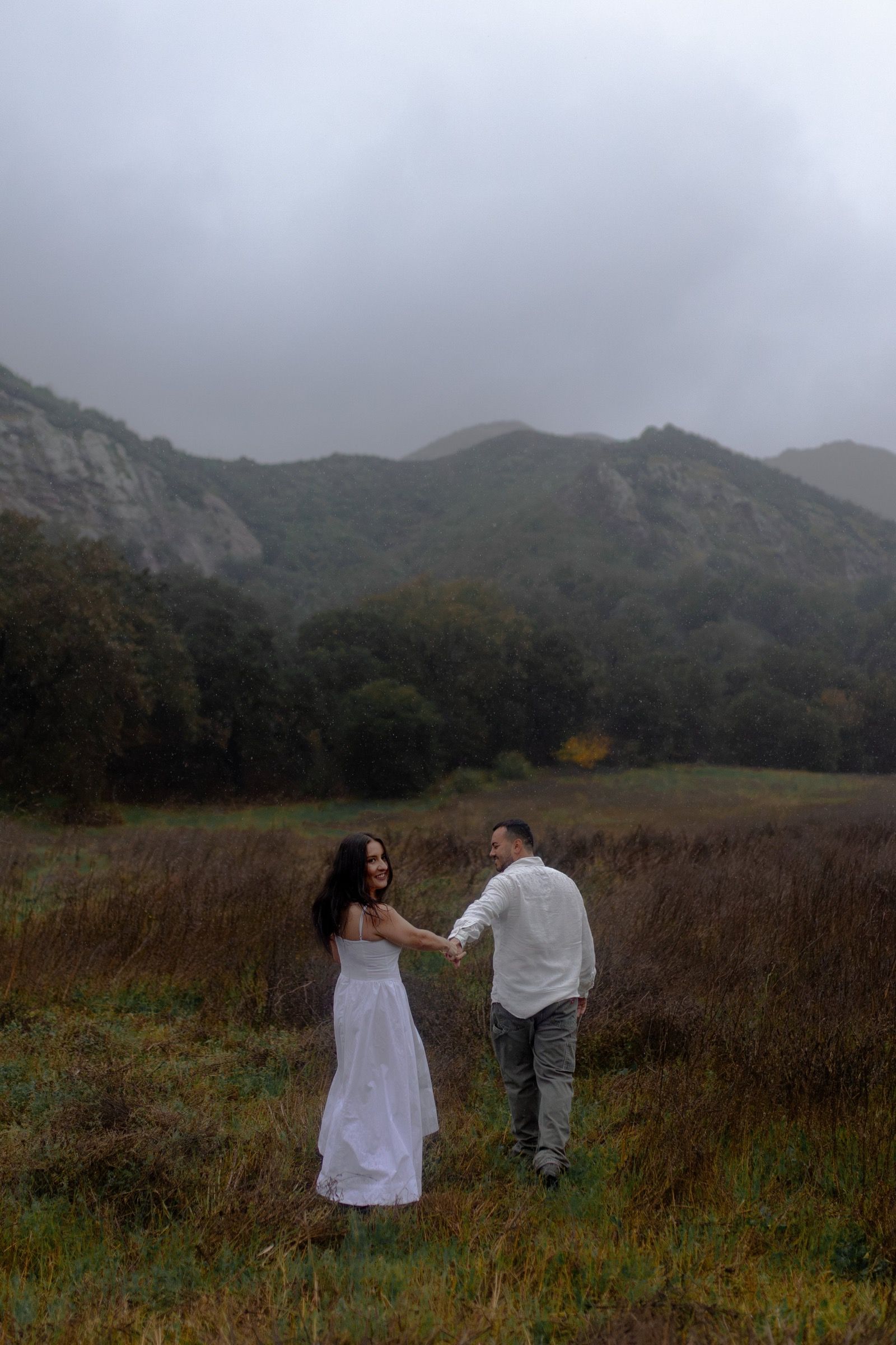 Monica and Eduardo dancing in a field below the mountains